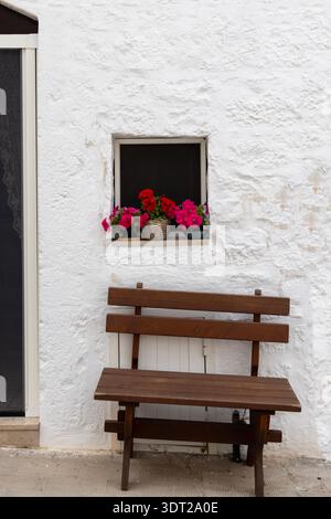 Malerische enge Straße mit weißem Haus, Bank und Blumentopf, typische Aussicht in Mittelmeerländern, Locorotondo, Italien, Apulien Stockfoto