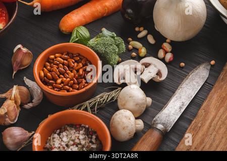 Mosaik aus frischem Gemüse, Nüssen und Gewürzen auf einem Küchentisch während der Zubereitung der Mahlzeiten Stockfoto