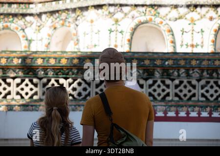Junges Paar, das nach oben blickt, männliche und weibliche Schultern, Rückansicht, bei Wat Arun. Stockfoto