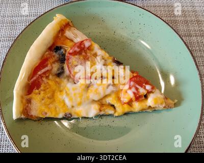 Pizzastück mit Huhn und Pilzen auf grüner Keramikplatte. Blick von oben. Kopierbereich. Nahaufnahme Stockfoto