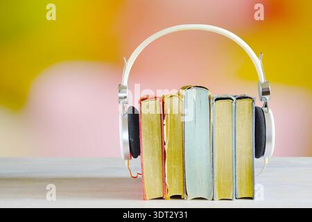 Hörbuch-Konzept mit Büchern und Kopfhörern auf glattem farbigem Hintergrund Stockfoto