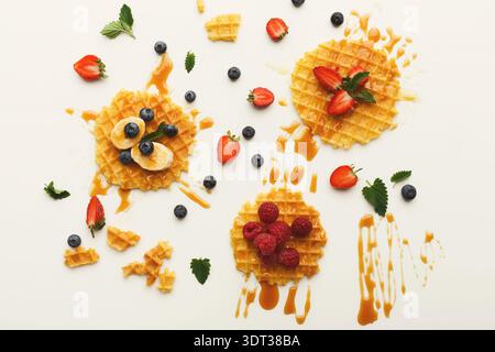 Sammlung verschiedener Waffeln mit Obst und Sirup auf einer hellen Oberfläche Stockfoto