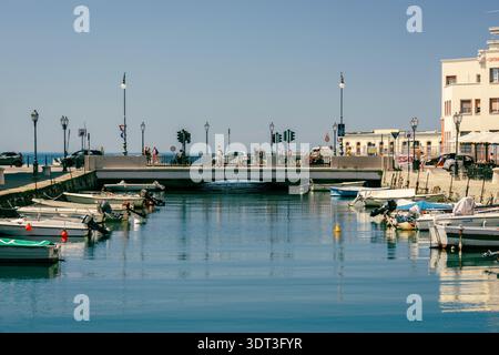 Ein malerischer Blick auf einen Kanal in Triest, Italien, mit mehreren kleinen Booten, die entlang der Docks ankern. Stockfoto