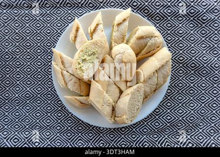In Scheiben geschnittene Baguette-Stücke mit KräuterKnoblauchbutter auf einem runden weißen Teller servieren Stockfoto