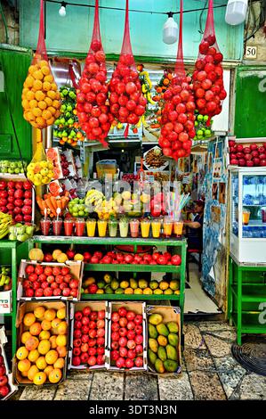 Händler verkaufen farbenfrohe Früchte und frischen Saft auf dem geschäftigen Markt der Altstadt in Jerusalem. Viele Leute sind einkaufen und genießen die Sehenswürdigkeiten. Stockfoto