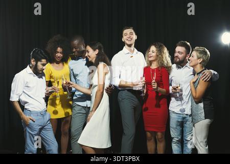 Eine Gruppe von Freunden genießt Drinks und feiert bei einem gesellschaftlichen Event in einer dunklen Umgebung Stockfoto