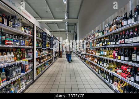 Dijon, Frankreich - 2. Februar 2026: Ein Mann mit einem Einkaufswagen spaziert zwischen Wein- und Spirituosenregalen. Diese Geschäft- und Einkaufsszene zeigt eine Person, die Alco kauft Stockfoto