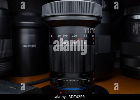 Nahaufnahme eines professionellen spiegellosen Kameraobjektivs mit Blendenmarkierungen und Fokusskala bei schlechten Lichtverhältnissen Stockfoto