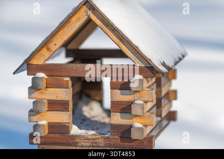 Das Dach des Vogelhauses und der Eingang sind mit detaillierter Baumstruktur bedeckt, Schneekristalle auf Schindeln, scharfer Fokus, handwerklicher Zimmerei sichtbar, intime Natur Stockfoto