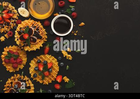 Waffle Collection mit Früchten und Sirupe auf dunkler Oberfläche, ideal zum Frühstück oder Dessert Stockfoto