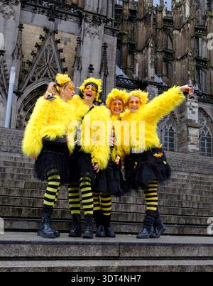 Während des Karnevals posieren Karnevalsfreunde in knallgelben Kostümen auf den Stufen des Kölner Doms Stockfoto
