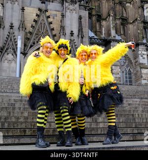 Während des Karnevals posieren Karnevalsfreunde in knallgelben Kostümen auf den Stufen des Kölner Doms Stockfoto