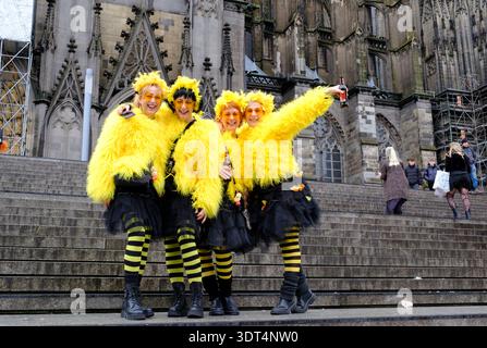 Während des Karnevals posieren Karnevalsfreunde in knallgelben Kostümen auf den Stufen des Kölner Doms Stockfoto