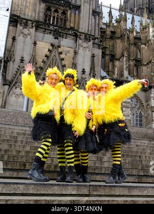 Während des Karnevals posieren Karnevalsfreunde in knallgelben Kostümen auf den Stufen des Kölner Doms Stockfoto