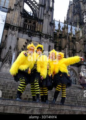Während des Karnevals posieren Karnevalsfreunde in knallgelben Kostümen auf den Stufen des Kölner Doms Stockfoto