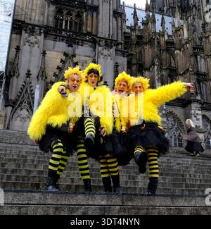 Während des Karnevals posieren Karnevalsfreunde in knallgelben Kostümen auf den Stufen des Kölner Doms Stockfoto