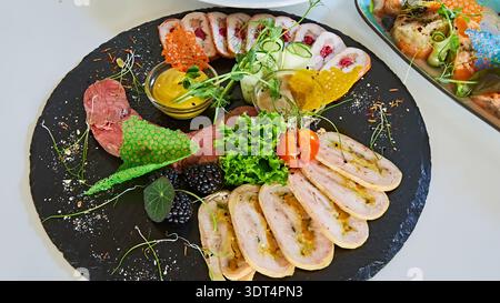 Luxuriöses Wurstschiefer mit handgefertigten Geflügelrouladen und gebratenem Fleisch mit lebhaften Tuiles, einer multisensorischen Darstellung von reichhaltigen Texturen und üppigen C Stockfoto