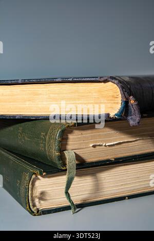 Alte Ausdrucke auf grauem Hintergrund. Ein Haufen alter gelber Hardcover-Bücher. Wirtschaft und Bildung, das Konzept des „Schulrückgangs“. Ein detaillierter Nahaufnahme-sid Stockfoto