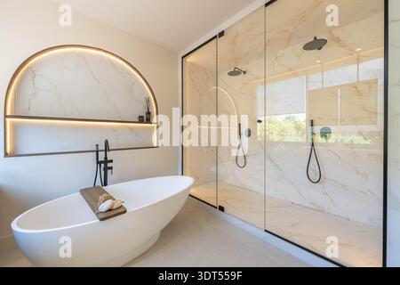 ein Bild eines luxuriösen renovierten Badezimmers mit freistehender Badewanne und Doppelduschen in mediterraner Immobilien Stockfoto