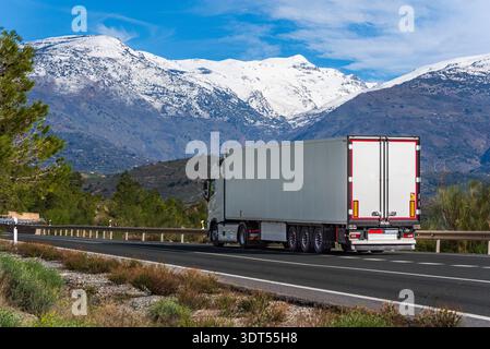 Gekühlter Sattelschlepper, der durch eine winterliche Berglandschaft fährt Stockfoto