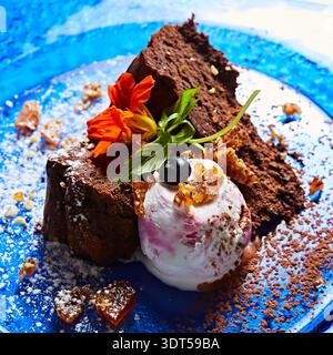 Gourmet-Schokoladenkuchen mit Beereneis und essbaren Blumen Stockfoto