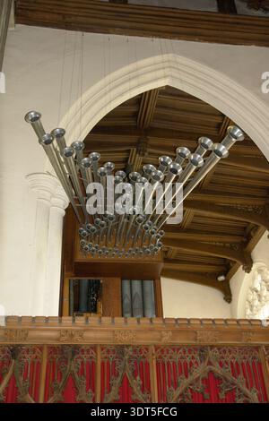 Horizontale Trompetenorgelpfeifen fächern sich dramatisch über einem geschnitzten hölzernen Chorschirm in einer mittelalterlichen englischen Pfarrkirche mit gotischen Bögen Stockfoto