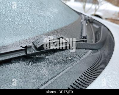 Nahaufnahme des gefrorenen Scheibenwischers des Autos, der bei kaltem Winterwetter mit Eis und Frost auf Glas bedeckt ist, detaillierte Textur von gefrorenen Wassertropfen auf dem Fahrzeug Stockfoto