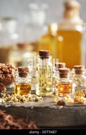 Verschiedene Aromatherapie-ätherische Öle in Glasflaschen mit Weihrauch, Myrrhe und getrockneten Kräutern Stockfoto