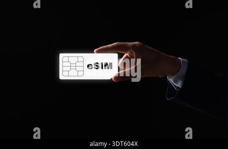 Geschäftsmann mit virtueller eSIM vor schwarzem Hintergrund, Nahaufnahme Stockfoto