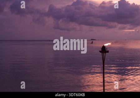 Tropischer Sonnenuntergang über ruhigem Meer mit Tiki-Fackel in Koh Phangan Stockfoto