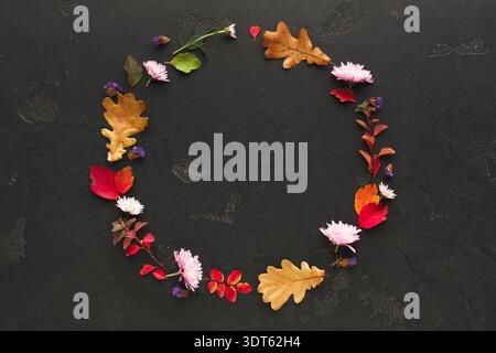 Kreative Collage aus Blättern und Blumen in kreisförmiger Form auf dunkler Oberfläche Stockfoto