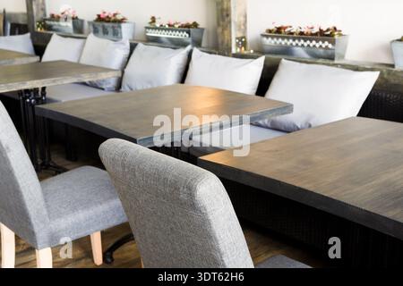Tische und Stühle sind in einem Essbereich mit Blumenkopfpflanzen in einem gemütlichen Raum angeordnet Stockfoto