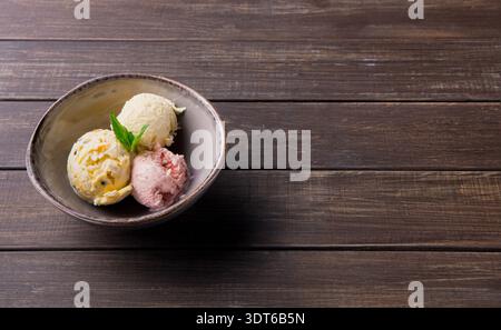 Verschiedene Eissorten serviert in einer Schüssel auf einem Holztisch in einem Café Stockfoto