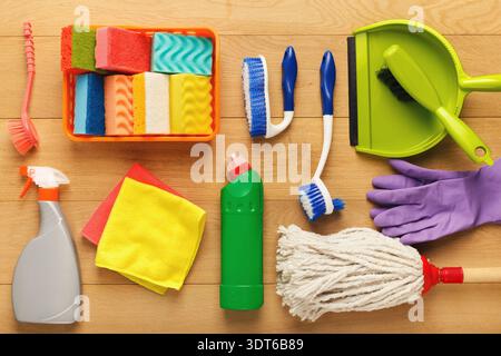 Sammlung von Reinigungsmitteln und -Werkzeugen, die auf einer Holzoberfläche für Haushaltsaufgaben angeordnet sind Stockfoto