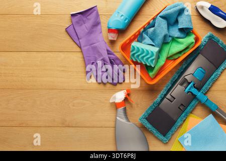 Sammlung von Reinigungsmaterialien und -Werkzeugen, die auf einer Holzoberfläche für Hausreinigungsaufgaben angeordnet sind Stockfoto
