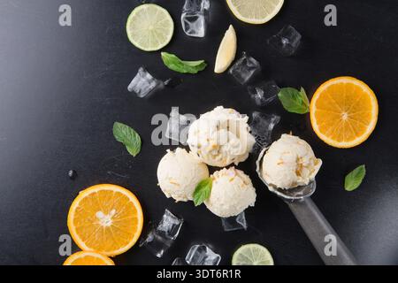 Eiskugeln mit frischem Obst und Minze auf dunkler Oberfläche mit Eiswürfeln Stockfoto