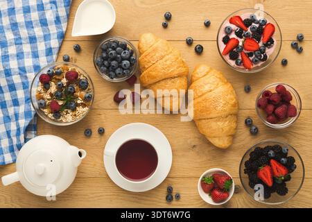 Sammlung von Frühstücksartikeln auf einem Holztisch mit Obst und Gebäck Stockfoto