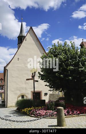 Kleine historische Kirche umgeben von blühenden Gärten und hellem Himmel in Forchheim, Forchheim, Bayern, Deutschland Stockfoto