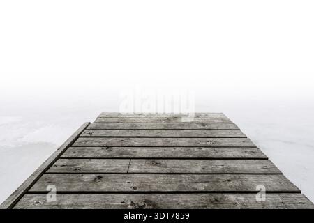 Pier in den Nebel. Holzsteg an nebeligen Tagen am See im Winter Stockfoto