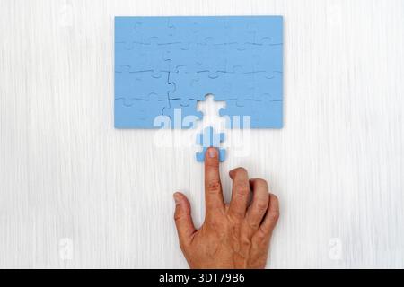 Hand das letzte Stück des Puzzles zur Vollendung der Aufgabe Stockfoto