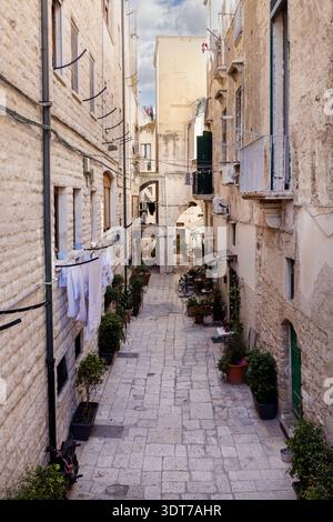 Bari, Italien, Apulien - 23. Mai 2024: Charmante, enge Straße von Bari Vecchia, typisch für die Mittelmeerländer. Steinhäuser, Topfblumen standi Stockfoto