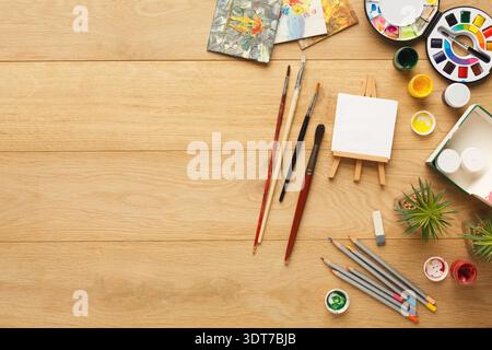 Eine farbenfrohe Kunstcollage auf einem Holztisch mit verschiedenen Werkzeugen und Zubehör in der Nähe basteln Stockfoto