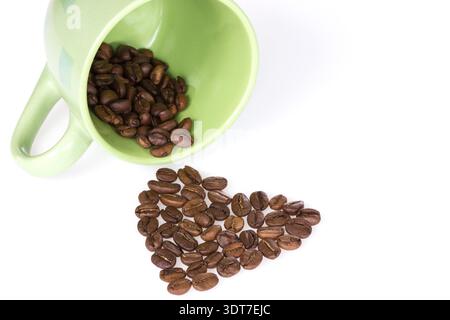 Grüne Tasse mit Kaffeebohnen bilden Form des Herzens Stockfoto