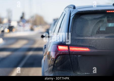 Rückseite des dunklen Kombiwagens mit Bremslichtern, eiskaltes Glas und Straßenschmutz, enger Rahmen mit flacher Feldrate auf einer geschäftigen Stadtstraße Stockfoto