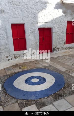 Hellrote Türen und weiße Wand mit typisch traditioneller Architektur mit einem blau-weißen Symbol für Neid, eine hübsche Straße in der türkischen Altstadt Stockfoto