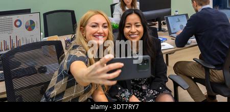 Glückliche multiethnische Geschäftskollegen lächeln und machen ein Selfie in einem modernen Coworking Office Stockfoto