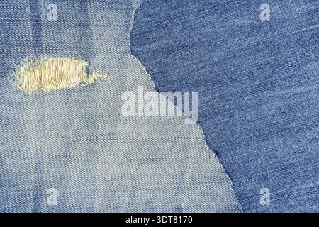 Hintergrund aus Denim-Stoff in blauer Jeans. Geriffeltes Denim-Material. Zerrissene blaue Jeans aus Denim Stockfoto
