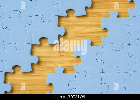 Hölzerner Hintergrund zwischen den Puzzleteilen. Entdecken und schließen Sie Lücken im Leben oder Geschäft Stockfoto