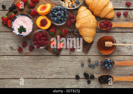Köstliches Frühstück mit Obst, Croissants und Joghurt auf Holztisch Stockfoto