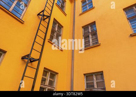 Altes orangefarbenes Industriebau mit einer Feuertreppe. Flachwinkelansicht Stockfoto